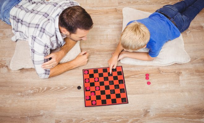 High,Angle,View,Of,Father,And,Son,Playing,Checker,Game